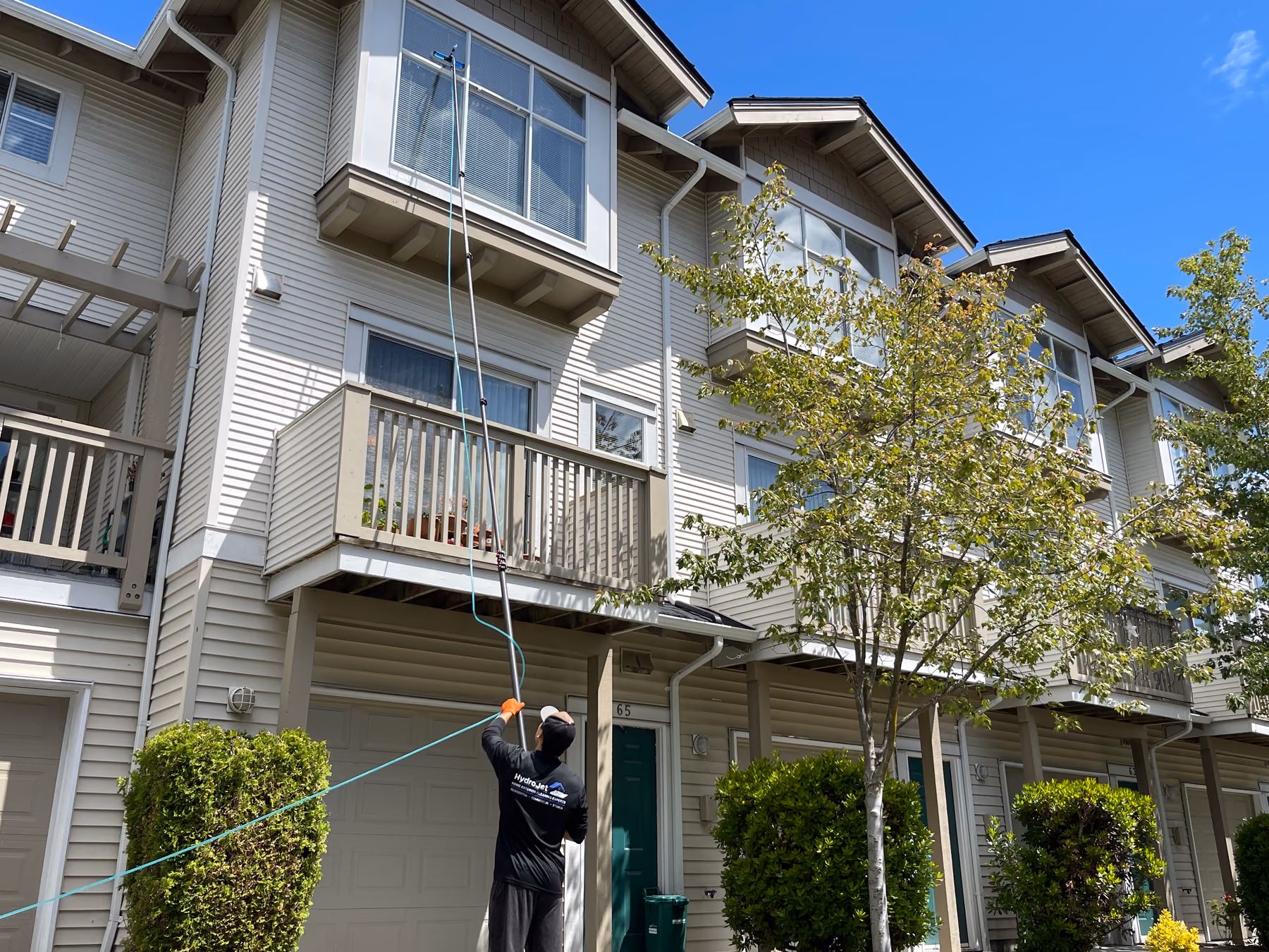 HydroJet crew member cleaning upper-storey windows at a Metro Vancouver strata property