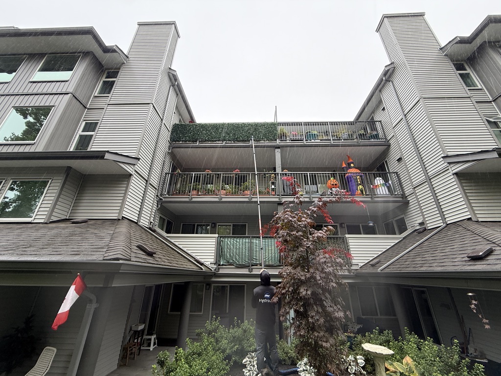 HydroJet crew member working on upper-level gutters at a multi-family property